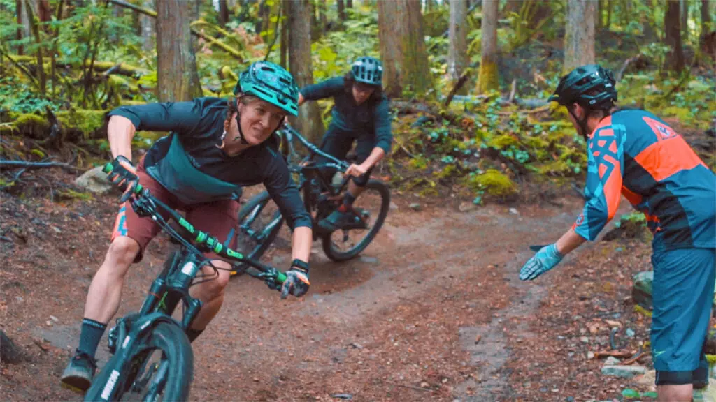 Three mountain bikers enjoying a thrilling ride down a trail in the woods.