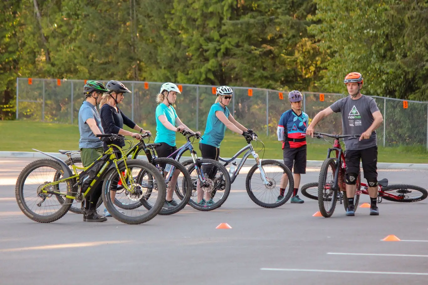 A group of people having an adventurous mountain biking lesson in a parking lot.