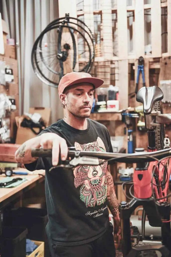 A person in a workshop adjusts a bicycle handlebar.