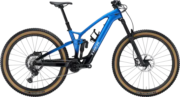A blue and black mountain bike with tan sidewall tires, full suspension, disc brakes, and a Trek logo on the frame, shown on a white background.